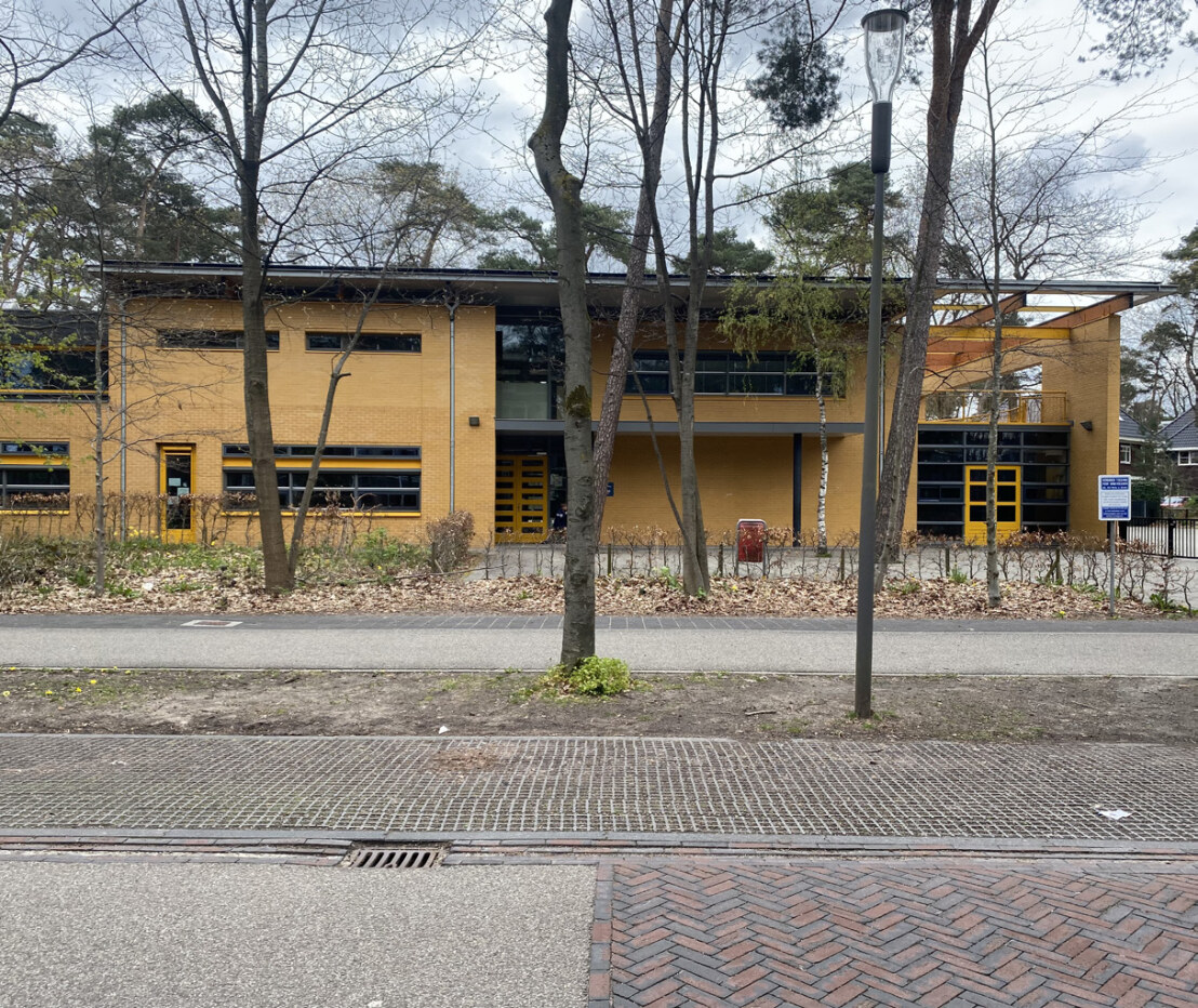 Precedent image showing an example of a school building integrated within an area with existing trees
