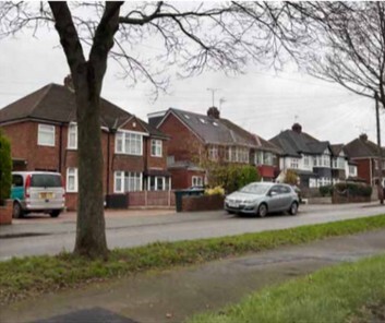 A photo of terraced houses with repeated archway entrances, bay windows and gables